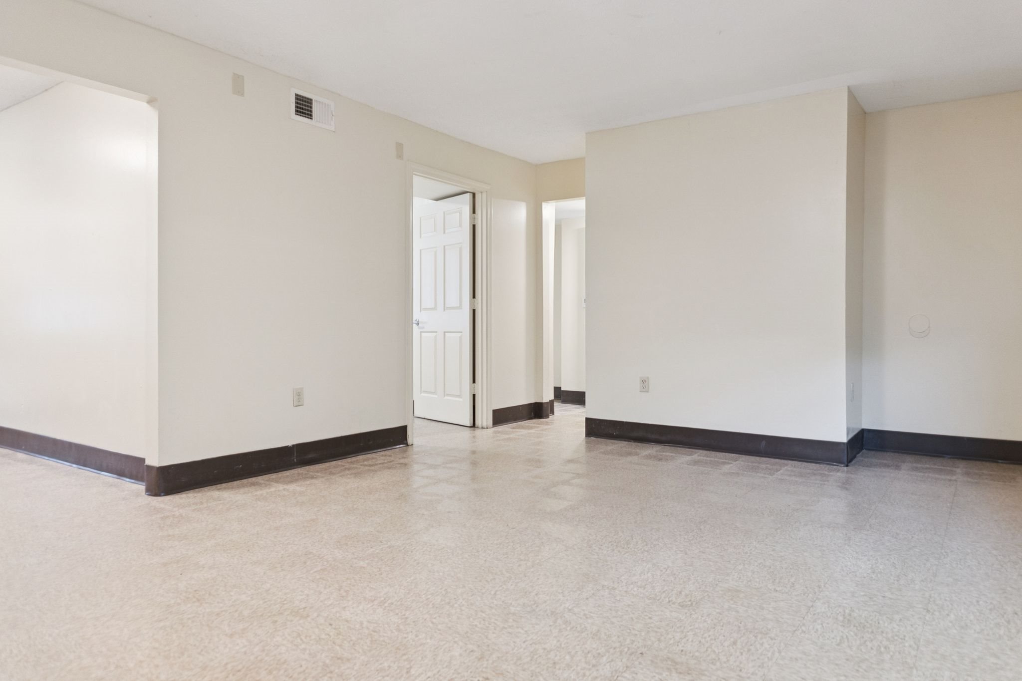 A spacious room with a door in the middle and another door at the end.